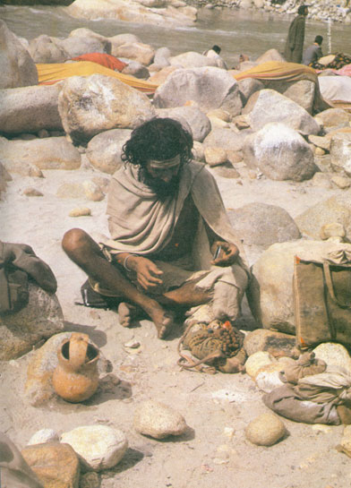 An ascetic takes stock of his meagre possessions while seated on the bank of a sandy glacial river. Unplanned exploitation by industry has taken away the vital timber resources which common hill folk depend on for their survival.